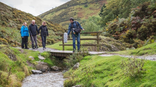 Four people walking along a path as part of a podcast recording at Carding Mill Valley, Shropshire